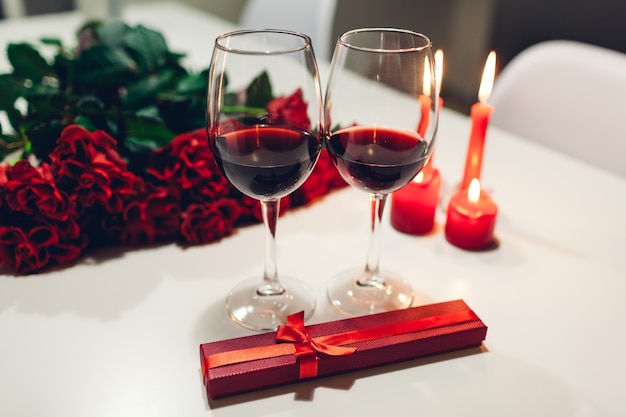 Festeggia San Valentino con vino, candele, rose rosse e confezione regalo a casa. Atmosfera romantica per gli innamorati