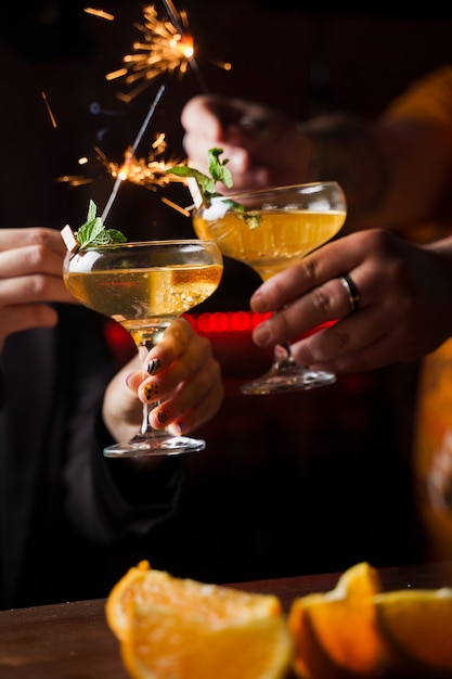 Festeggiamo il capodanno 2022 con fuochi d'artificio e cocktail bevuti. Menta con fetta d'arancia in un bicchiere da cocktail pieno di cocktail alcolici.