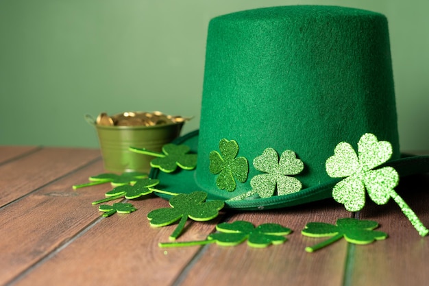Festeggiamo il giorno di San Patrizio con un tocco di fortuna cappello verde, quadrifogli e monete su un tavolo di legno