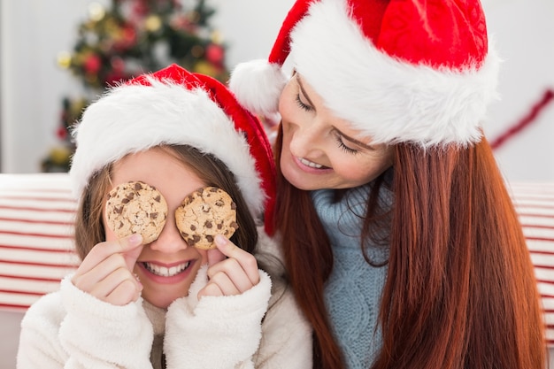 Festiva madre e figlia sul divano con i biscotti