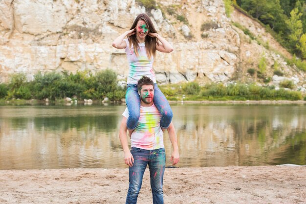 Festival holi, turismo estivo e concetto di natura - giovane donna attraente che si siede sulle spalle su di lei