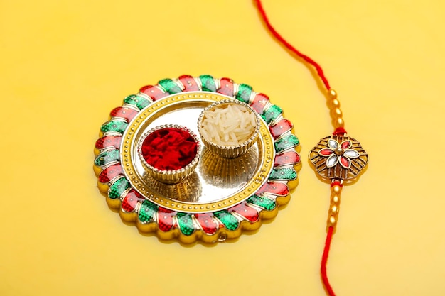 Festival indiano raksha bandhan puja thali e rakhi o cinturino da polso su sfondo giallo