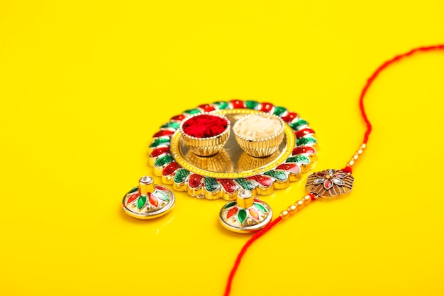 Festival indiano raksha bandhan puja thali e rakhi o cinturino da polso su sfondo giallo