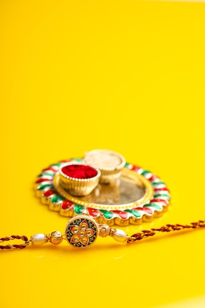 Festival indiano raksha bandhan puja thali e rakhi o cinturino da polso su sfondo giallo