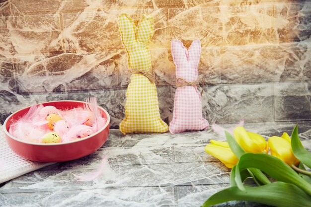 Festosa Pasqua sfondo luminoso ciotola rosa con uova colorate e soffici piume rosa che creano morbidi coniglietti tulipani gialli
