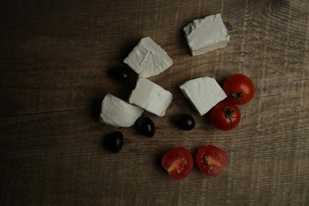 feta affetta olive nere e pomodorini su uno sfondo di legno