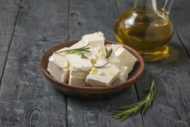 Feta affettata in una ciotola di argilla e olio d'oliva su un tavolo di legno. Formaggio naturale prodotto con latte di pecora.