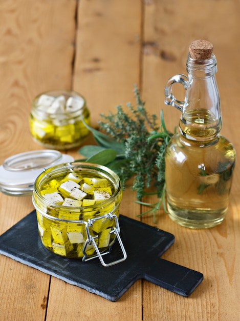 Feta marinato in un vaso di vetro, spezie e olio d&#39;oliva su un fondo di legno