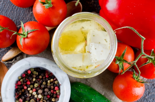 Feta piccante marinata in un barattolo e verdure per insalata.