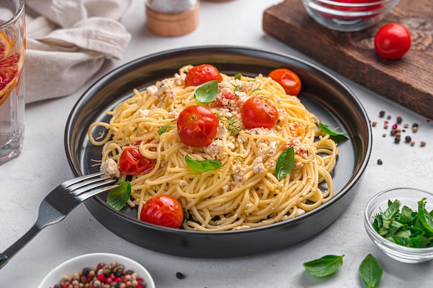 Fetapasta con pomodorini feta e basilico su sfondo grigio Vista laterale del primo piano