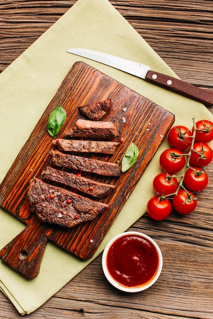 Fetta di bistecca fritta con salsa di pomodoro rosso sul tagliere di legno