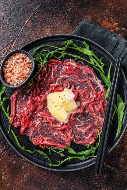 Fetta Di Carpaccio Di Manzo, Rucola E Parmigiano. Sfondo scuro. Vista dall'alto.