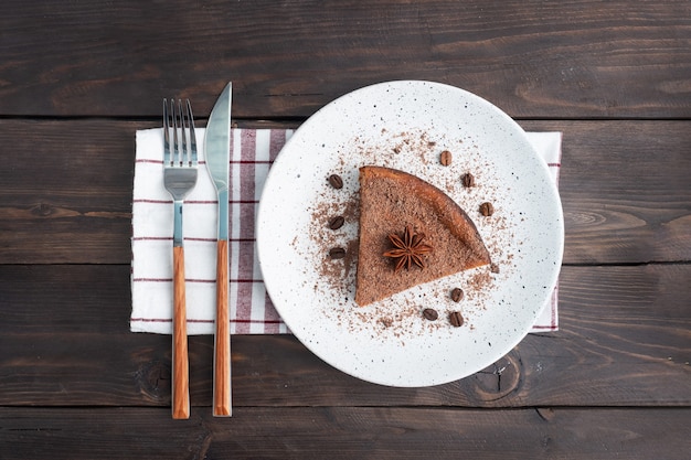 Fetta di casseruola di cagliata al cioccolato su un piatto, una fetta di torta con cioccolato e caffè. Tavolo rustico in legno scuro. vista dall'alto copia spazio