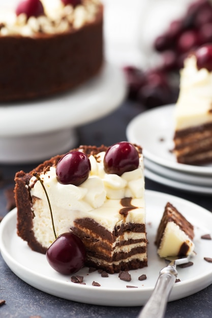 Fetta di cheesecake al cioccolato con ciliegie su un piatto bianco