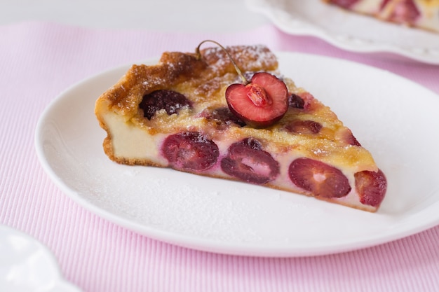 Fetta di clafoutis alla ciliegia sul piatto sul tavolo rosa