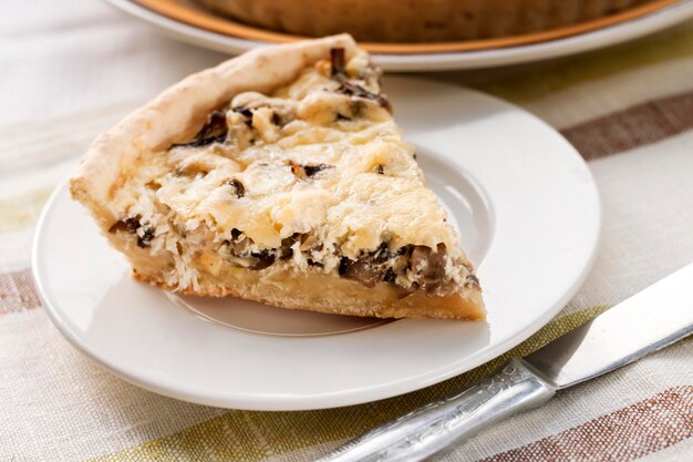 Fetta di crostata di pollo con funghi e formaggio su un piatto