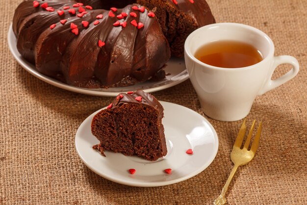 Fetta di deliziosa torta al cioccolato fatta in casa decorata con piccoli cuori di caramello sul piattino