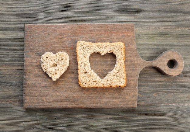 Fetta di pane con taglio a forma di cuore su fondo di legno