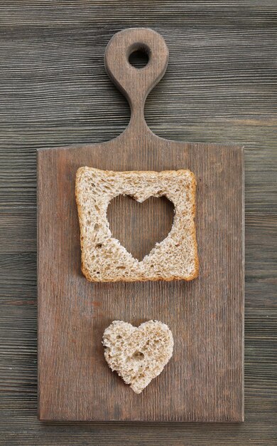 Fetta di pane con taglio a forma di cuore su fondo di legno