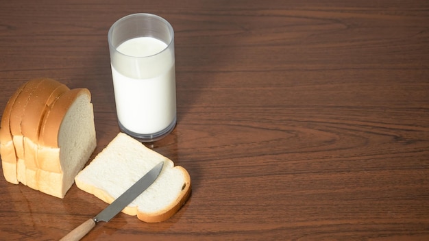 Fetta di pane della pagnotta con il coltello con un bicchiere di latte sulla vista superiore dello spazio della copia del tavolo