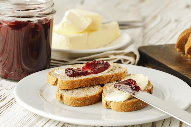 Fetta di pane fresco con burro e marmellata sul tavolo