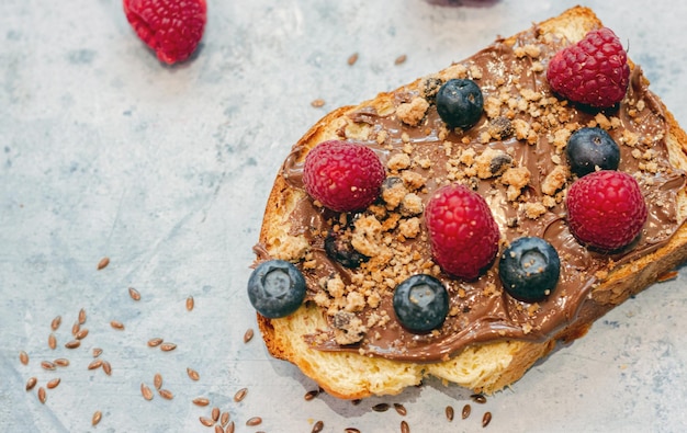 Fetta di pane secco come toast con lamponi e mirtilli al cioccolato