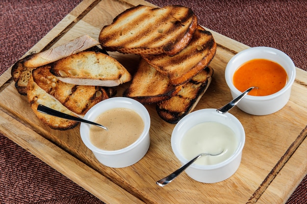 Fetta di pane tostato arrostito impanato con formaggio e sesamo scivolato in salsa su una tavola di legno