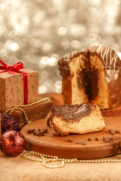 Fetta di panettone al cioccolato sul tagliere di legno con ornamenti natalizi