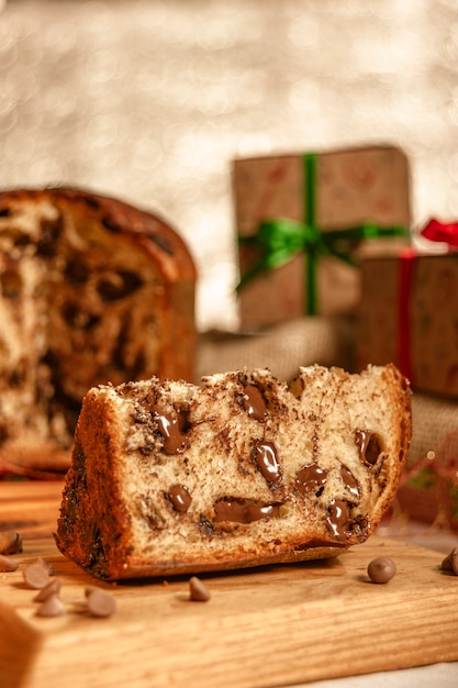 Fetta di panettone al cioccolato sul tagliere di legno con ornamenti natalizi