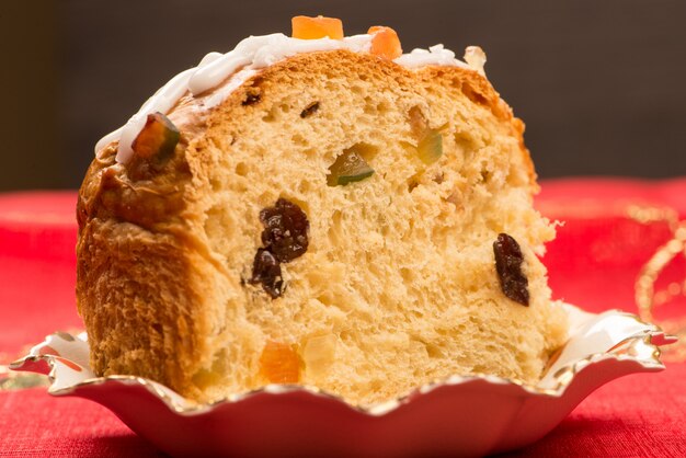 Fetta di panettone sul tovagliolo rosso e sfondo nero