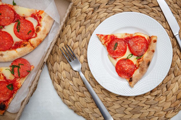 Fetta di pizza al pepperoni su un piatto bianco