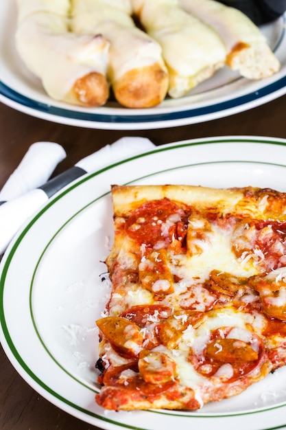 Fetta di pizza con salsiccia e peperoni freschi sul tavolo in un ristorante italiano.