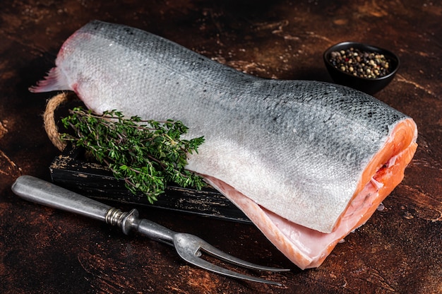 Fetta di salmone crudo tagliato in un vassoio di legno con timo