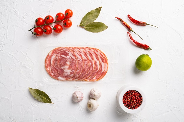 Fetta di salsiccia di chorizo di salame di maiale affumicato in confezione sottovuoto, su sfondo di tavolo in pietra bianca, vista dall'alto piatta