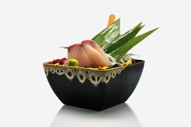 Fetta di sashimi di Hamachi in ciotola nera su fondo bianco