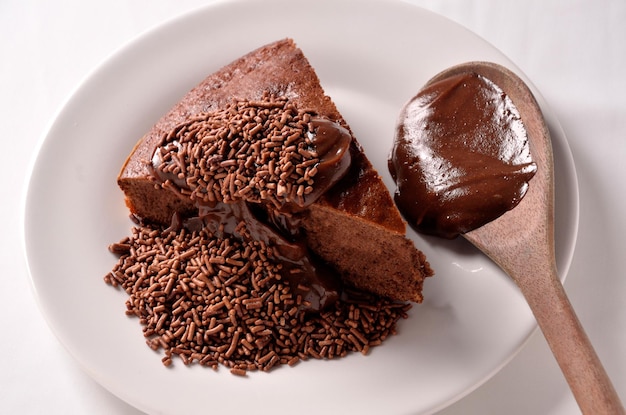 fetta di torta al cioccolato con ganache cosparsa su piatto bianco con cucchiaio di legno