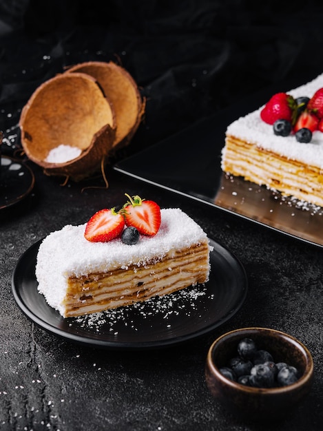 Fetta di torta al cocco con fragole e mirtilli