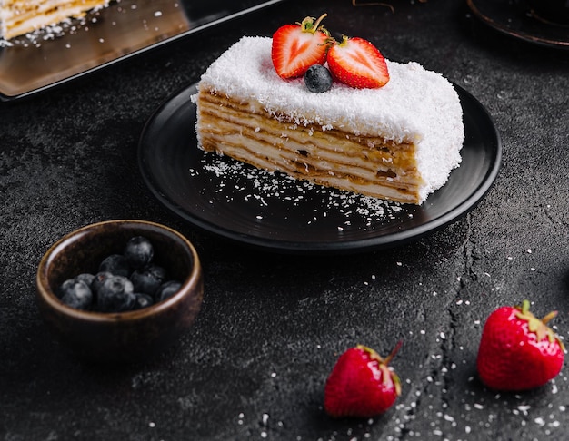 Fetta di torta al cocco con fragole e mirtilli