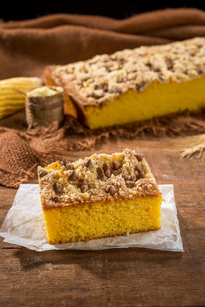 Fetta di torta di mais quadrata su legno con torta di mais sullo sfondo.