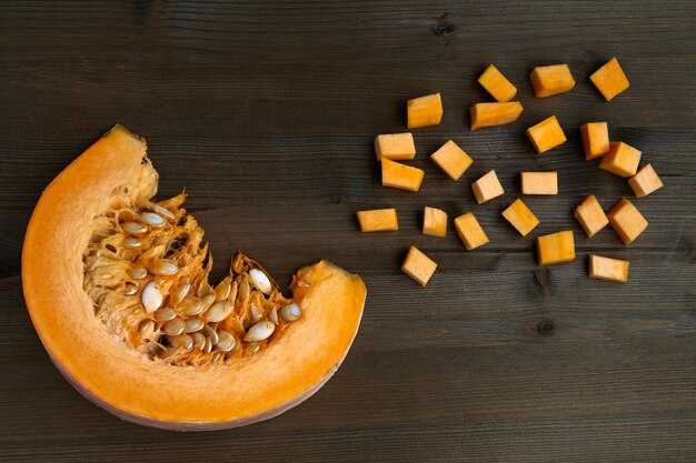 Fetta di zucca fresca biologica e tagliata a dadini su un tavolo di legno scuro. Produzione di marmellate fatte in casa. Vista dall'alto. Disposizione piatta