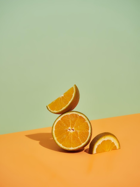 Fetta e segmento di mezza arancia in una composizione moderna Elementi posti in equilibrio su uno sfondo diagonale a due colori Luce dura con ombre
