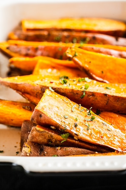 Fette al forno della patata dolce con le spezie in teglia da forno. Concetto di cibo sano vegan.