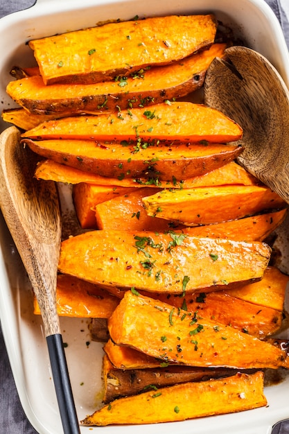 Fette al forno della patata dolce con le spezie in teglia da forno. Concetto di cibo sano vegan.