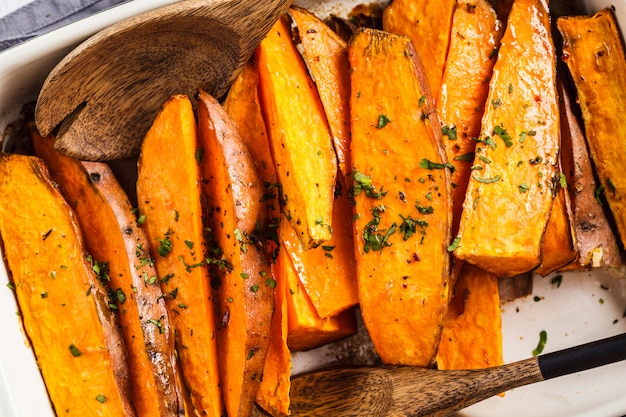 Fette al forno della patata dolce con le spezie in teglia da forno. Concetto di cibo sano vegan.