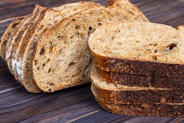 Fette del pane fresco sul tagliere contro fondo di legno bianco