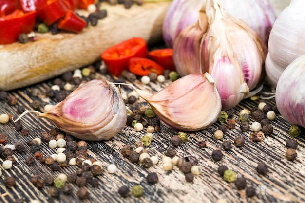 Fette di aglio amaro maturo e altre verdure, tavolo da cucina durante la cottura degli alimenti, primo piano