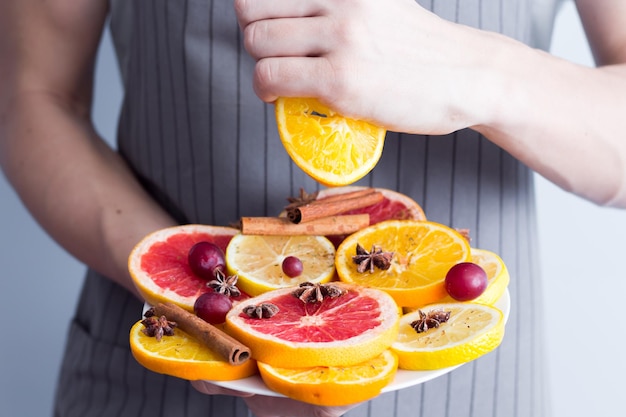 Fette di arance limoni e pompelmi su tavola di legno vintage Agrumi con anice stellato cannella mangiare sano con vitamine naturali tenendo le mani in una ciotola