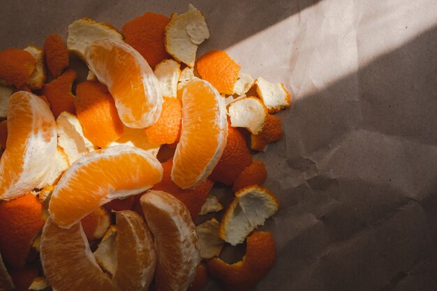 Fette di arancia e buccia alla luce del sole su carta