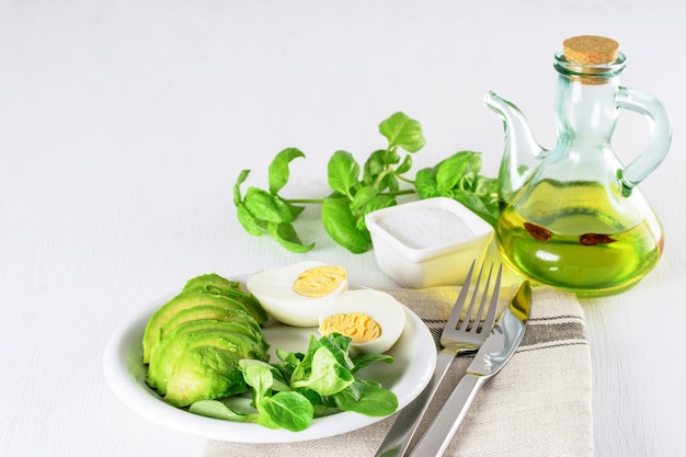 Fette di avocado fresco, uovo sodo e lattuga fresca con olio d'oliva