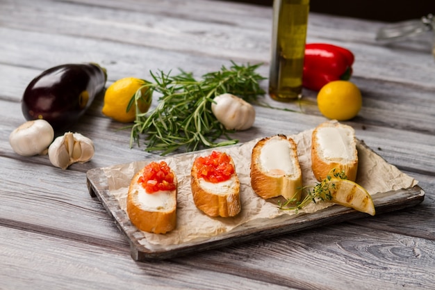 Fette di baguette con verdure. Toast e pezzo di limone. Bruschette croccanti al pomodoro. Esempio di cibo italiano.